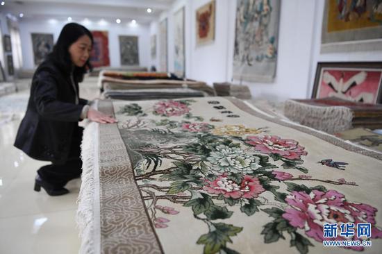 黄晶蓉在天水新天丝毯有限公司成品展室内查看丝毯成品(4月12日摄)。新华社记者 杜哲宇 摄