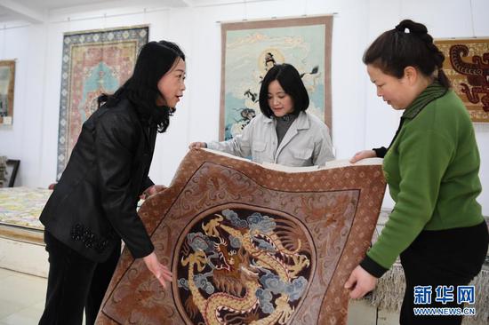 黄晶蓉(左一)在天水新天丝毯有限公司成品展室内和徒弟交流丝毯织造技艺(4月14日摄)。新华社记者 杜哲宇 摄