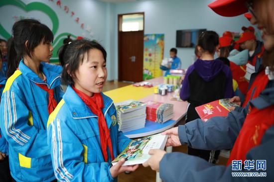 4月22日,在兰州新区第二小学,中建三局的志愿者给孩子们赠书。新华社记者 杜哲宇 摄