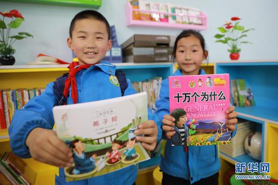 4月22日,在兰州新区第二小学,孩子们展示收到的新书。新华社记者 杜哲宇 摄