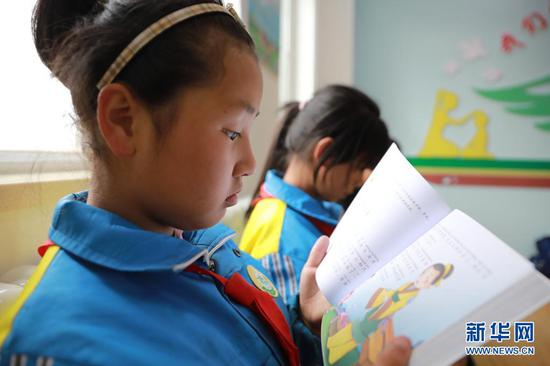 4月22日,在兰州新区第二小学,孩子们在翻阅新书。新华社记者 杜哲宇 摄