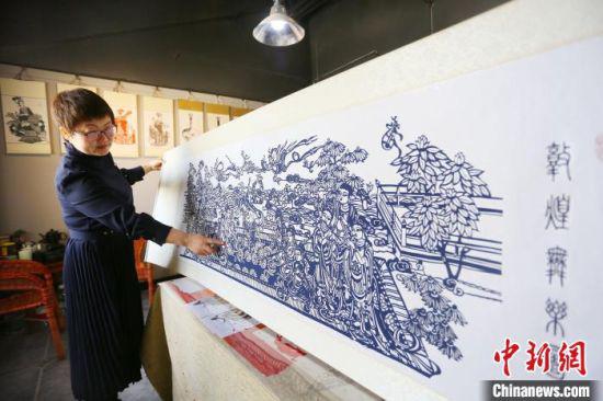 4月下旬,庄生娟向记者介绍耗时两个月的剪纸作品《敦煌舞乐图》。 高展 摄