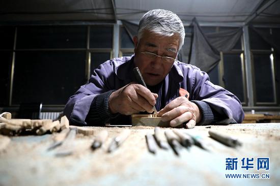 图为团队成员李俊林在雕刻雀替。
