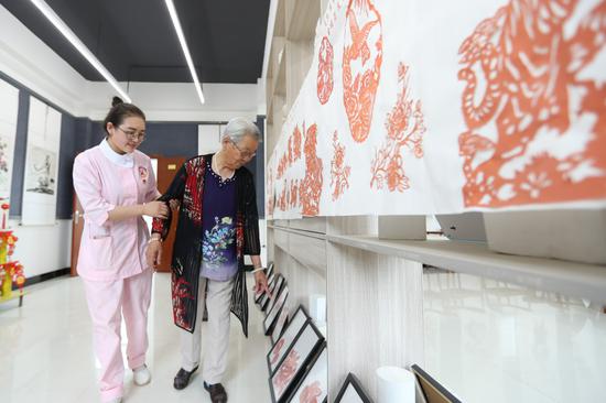 6月23日,在甘肃省庆阳市养老综合服务中心,入住老人介绍自己的剪纸作品。新华社记者 马希平 摄