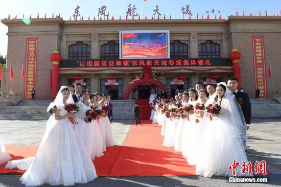 2019年,以“让祖国见证幸福”为主题的专场集体婚礼举行,新人们在酒泉东风航天城前集体合影。 中新社发 汪江波 摄