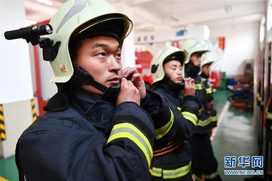 李志亮(左一)和队友穿戴消防救援服,准备执行任务(4月12日摄)。