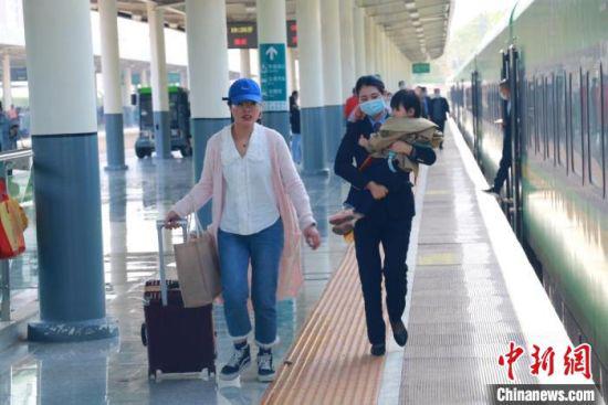 “五一”期间,中国铁路兰州局集团有限公司兰州客运段列车员,帮“妈妈旅客”抱孩子。 陈达 摄