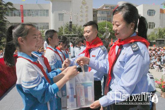 图为庆城县税务局党委委员、副局长司继华为贫困儿童赠送学习用品。