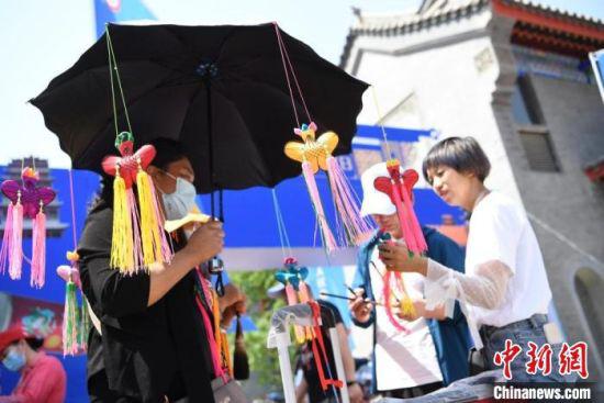 端午节期间,甘肃“非遗+民俗”游受追捧。图为在假日期间举行的非遗节会上,游客挑选手工香包。 杨艳敏 摄