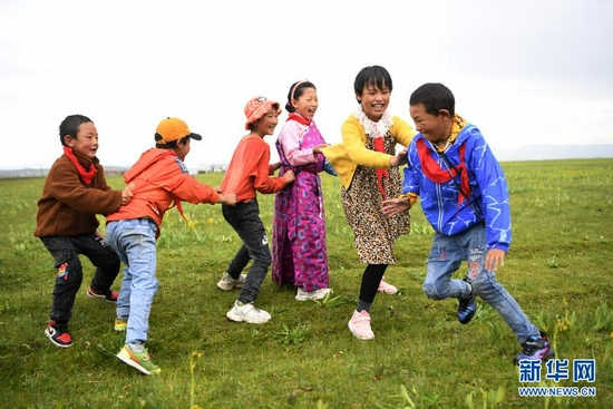 7月14日,河曲马场小学的孩子们在草原上做游戏。新华社记者 陈斌 摄