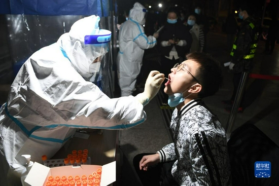 10月21日凌晨，在兰州市城关区农民巷一核酸检测采样点，医护人员进行核酸采样。新华社 范培珅 摄