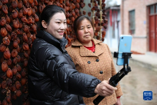 12月10日，王小桦（左）在陇南市康县寺台镇罗湾村和村民一起通过电商平台直播带货。新华社记者 陈斌 摄