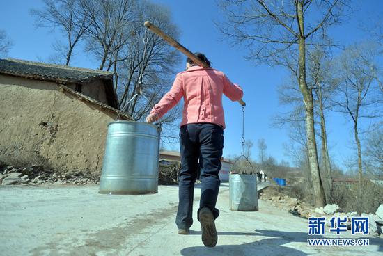 甘肃省渭源县田家河乡元古堆村的村民在引洮工程一期的自来水还未到达家中之前从村里唯一的水源往家里担水。(新华社记者范培珅2014年12月28日摄)