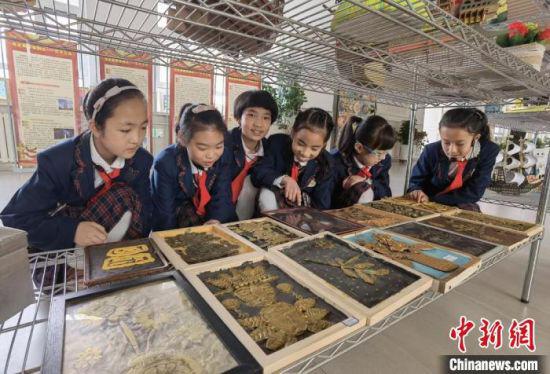 图为兰州新区实验小学小学生欣赏同学手工作品。 刘玉桃 摄