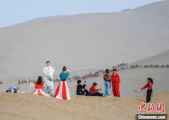 图为游客在鸣沙山月牙泉拍照游玩。 王斌银 摄