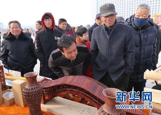 当地群众在观看榫卯木制手工作品(刘欣瑜 摄)