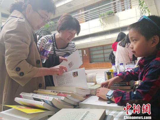 在主会场之外,读者读书会还设置了闲置图书置换专区,6岁的小学生王之藩为他和爸爸的闲置图书找到了一位“新主人”。 史静静 摄