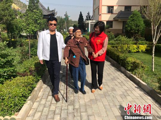 图为入住七里河区半山民族养老院的老人在志愿者和家人的陪同下散步。 达媛 摄