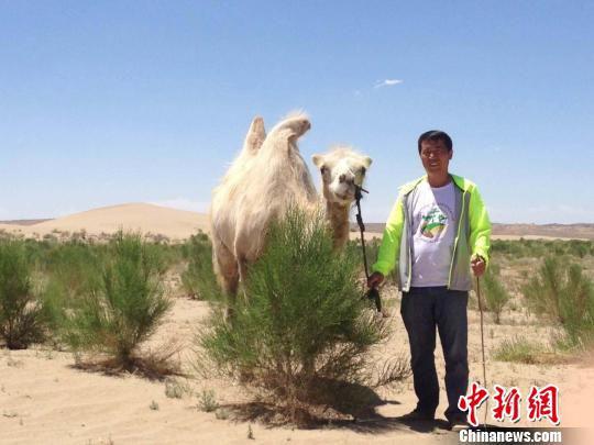 图为马俊河与沙漠上种植后长成的梭梭林合影。(资料图) 钟欣 摄