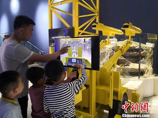 图为家长陪同孩子操作智能“采矿机器人”,体验采矿乐趣。 魏建军 摄