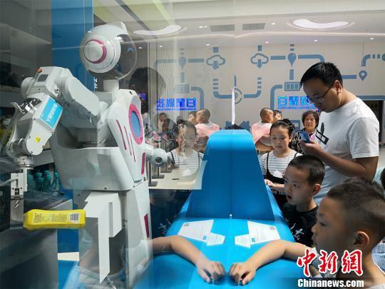 6月1日,甘肃科技馆举办“玩转科学欢度六一”系列活动。各种智能机器人“组团”伴儿童们过节。图为智能售货机器人扮起“服务员”给孩子们卖零食。 魏建军 摄