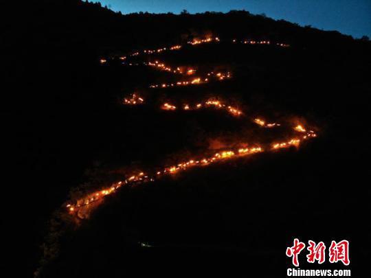 6月14日至18日,第三届陇南文县白马人·民俗文化旅游节举行。图为火把星星点点从山顶奔腾而下,顺着蜿蜒山路呈现“S”形。 杨艳敏 摄