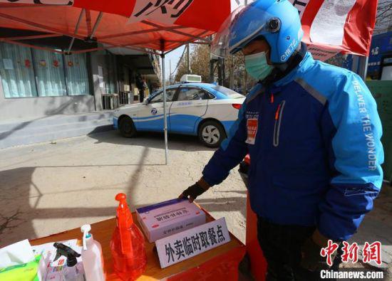 图为外卖小哥陈强将配送物品放置在临时取餐点。 高康迪 摄