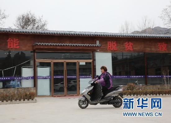 3月13日,余彩红骑车经过扶贫车间。新华社记者张玉洁 摄