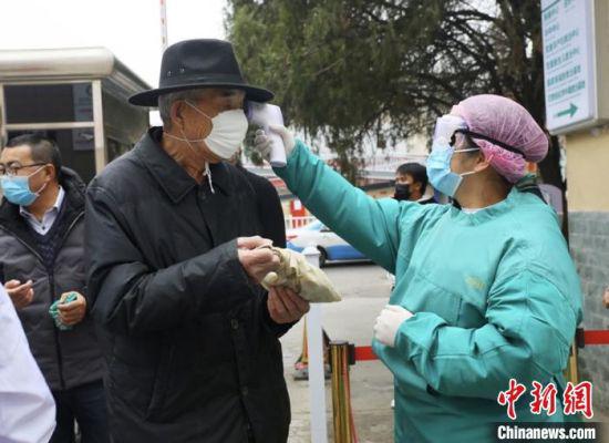 2月17日,甘肃省城医院入口处,医生为就诊者测体温。 闫姣 摄