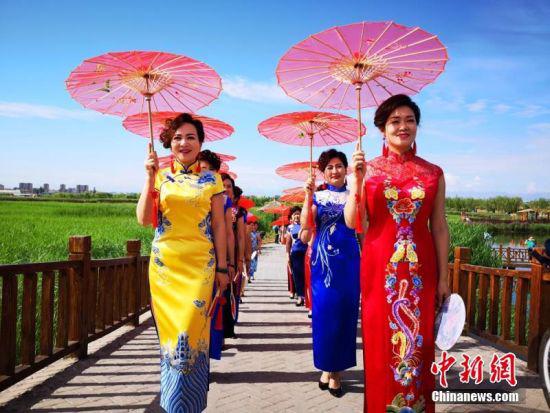 6月24日,甘肃张掖市的旗袍爱好者在张掖市国家湿地公园走秀展示旗袍之美。吴学珍 摄