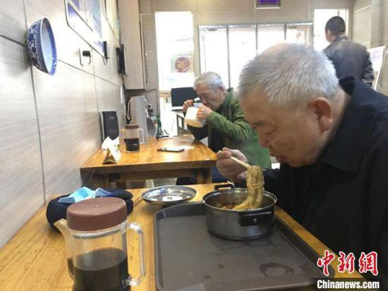 近日,甘肃省餐饮服务单位全面恢复堂食就餐,顾客隔凳(椅)就座,间隔保持在1米以上。图为兰州民众自带碗到牛肉面馆“吃牛大”。 张婧 摄