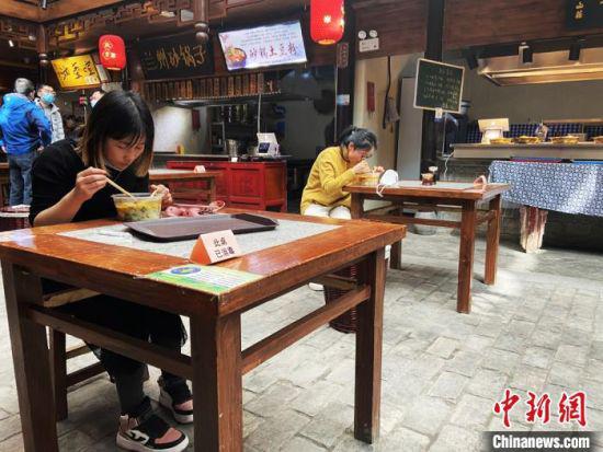 图为兰州中心食客单人单桌、同向进行就餐。 高康迪 摄
