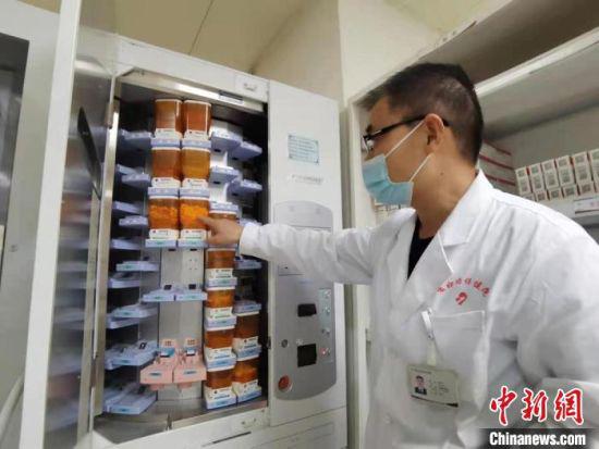 图为在住院部药房工作8年时间的主管药剂师杨天才向记者展示全自动片剂摆药机。 张婧 摄