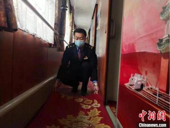 图为兰州客运段列车员小心铺好垫子,以防乘客摔倒。 陈达 摄