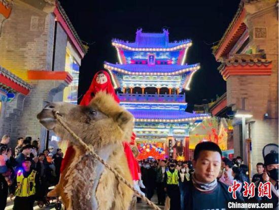 图为驼队与人群“再现”古丝绸之路繁荣盛况,引得市民和游客客“梦回”千年以前。 刘芯羽 摄
