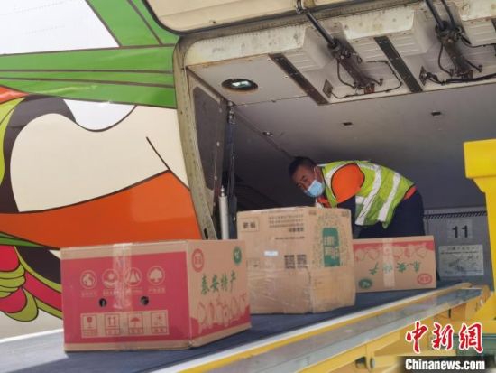 图为装卸工猫腰弓身在飞机腹仓内装卸货物。 杨娜 摄