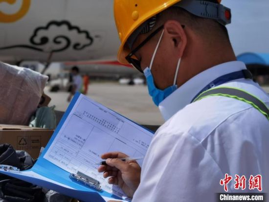 近日,兰州中川机场内,负责航班货物装卸的工人在高温下工作。图为对照行李单。 杨娜 摄