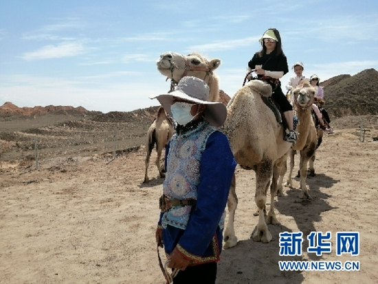安自发牵着骆驼带游客体验丹霞观光。新华网发 （宋燕 摄）