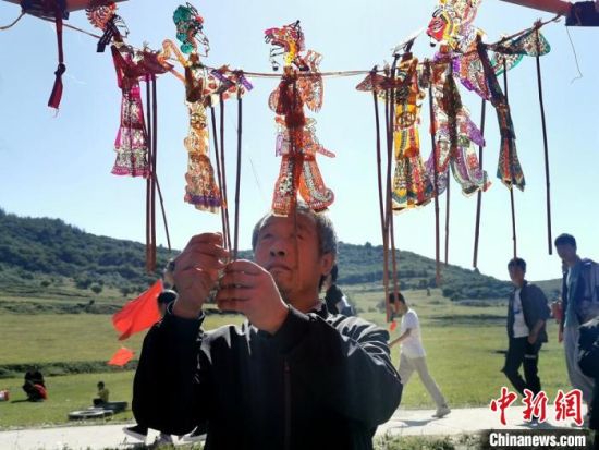 图为村民展示皮影。 秦亭镇政府供图