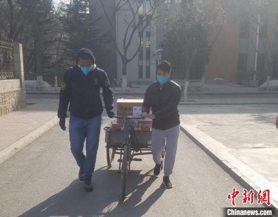 图为阿布(左)和泽广(右)在校园中用三轮车运送待发放中药。受访者供图