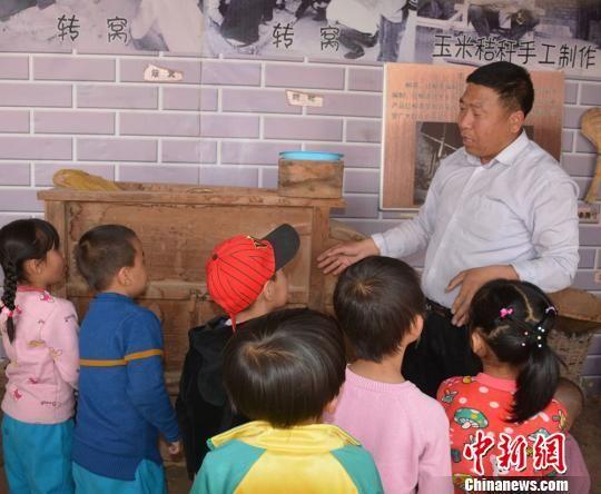 图为小朋友听工作人员讲解农具用途。 郭红 摄