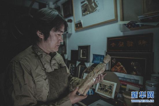甘肃文化的元素早已融入于刘志刚的艺术创作中,图为他正在展示修复的文物。