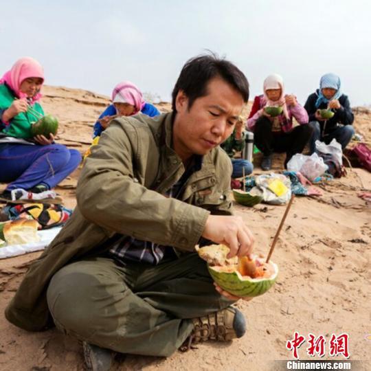 图为马俊河和压沙人中午在沙丘上“西瓜就着馍馍”吃午餐。(资料图) 钟欣 摄