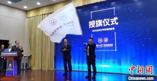 图为李玉民为兰州大学科技园有限责任公司总经理邓毓博授营旗。