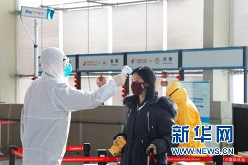 兰州中川国际机场航站楼入口处,工作人员对旅客进行体温检测。李今蓉摄