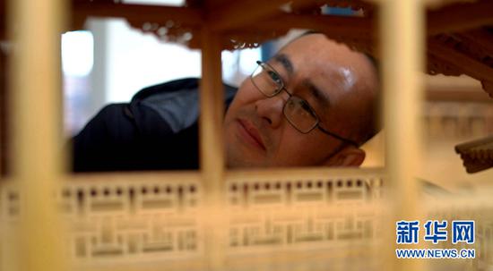 图为丁沙金在查看微缩古建筑作品内部结构。