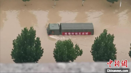 图为7月21日郑州东部地区被洪水围困,一辆军车在洪水中破浪前行。 张佳琪 摄