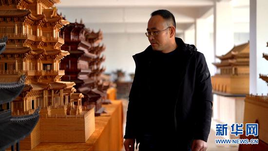 图为丁沙金在传习所展厅内观看微缩古建筑作品。