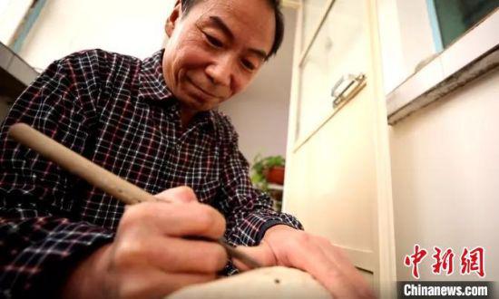 图为赵德成手持刻刀,精心打磨。 卢玉 摄