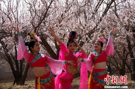 资料图。2016年4月,参加敦煌李广杏花节演出的演员在杏花园中拍照。 张晓亮 摄